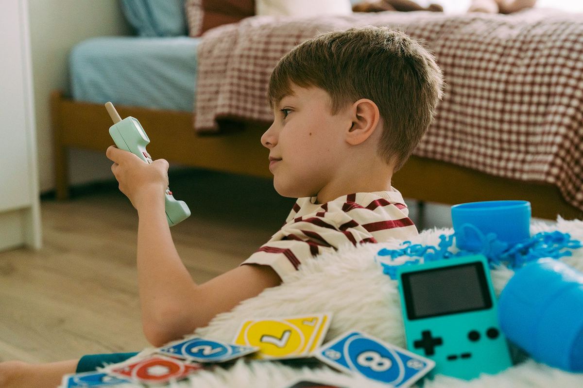 A boy holding the Waffle Home handset mid-conversation, card games and toys spread out around him.